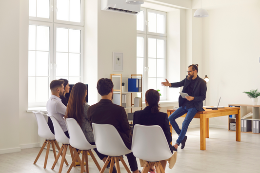 A group of people attentively listening to a coach as they plan their projects and work towards realizing their dreams. This image embodies teamwork, motivation, and the pursuit of personal goals.